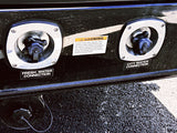 Close-up of an RV rental's fresh and city water connections. A warning label advises sanitizing the tank for safety.