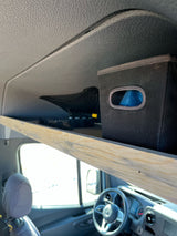 Inside an RV rental: overhead wooden shelf with storage bin/net, and the front cabin with Mercedes dashboard.