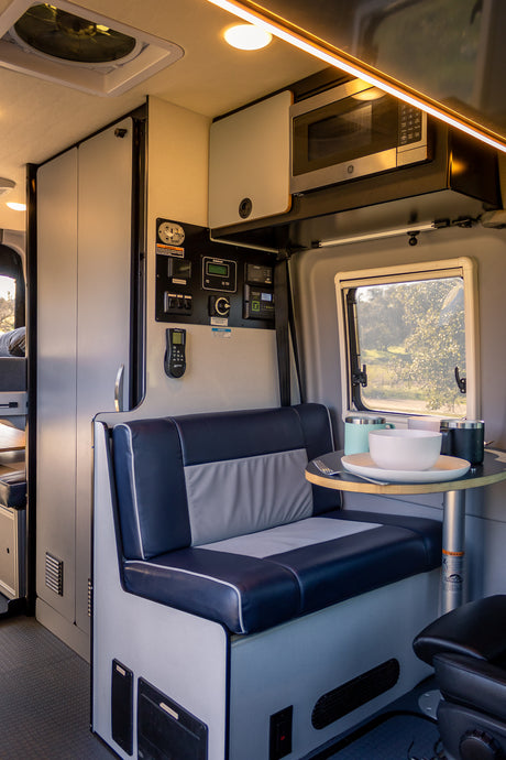Explore this spacious rv rental interior, featuring a cozy dining booth, microwave, and comprehensive control panel.