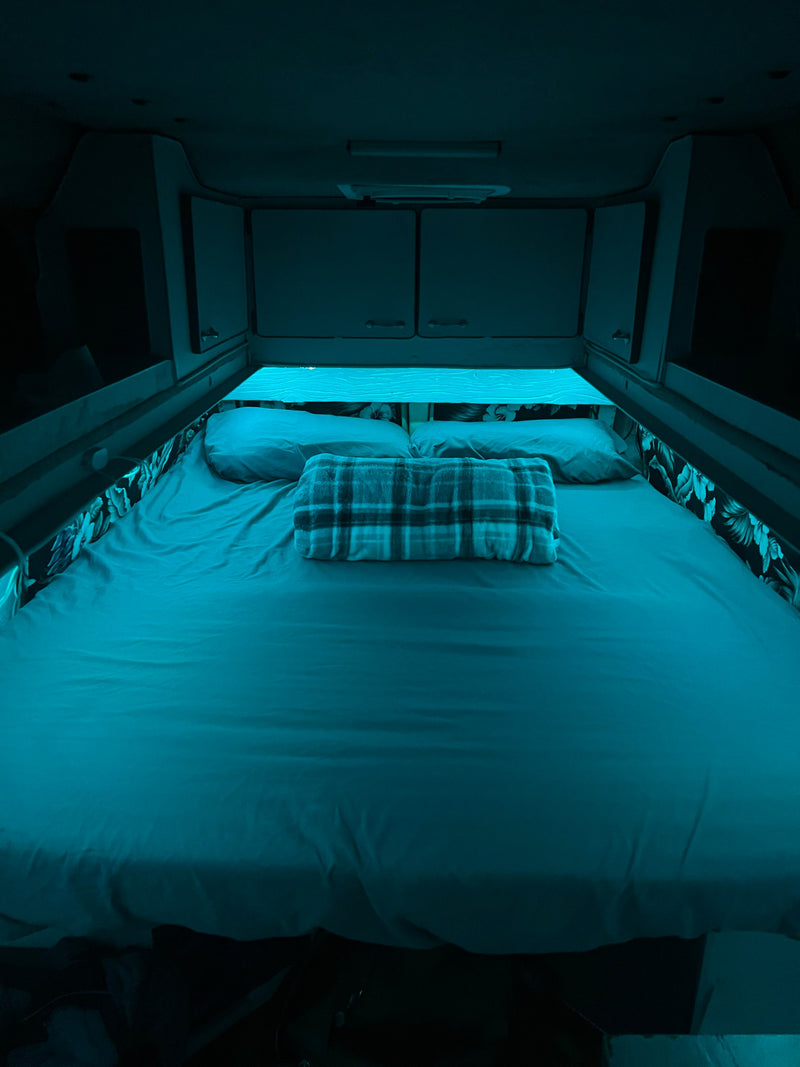  perfect for off-grid travel and exploration.|Cozy RV rental interior featuring a neatly made bed and a compact kitchenette with a decorative basin and faucet.|RV rental kitchen: a compact space with sink — photo 11