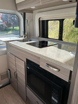 Stylish RV rental kitchen featuring a speckled countertop, sink, induction cooktop, and a built-in microwave.