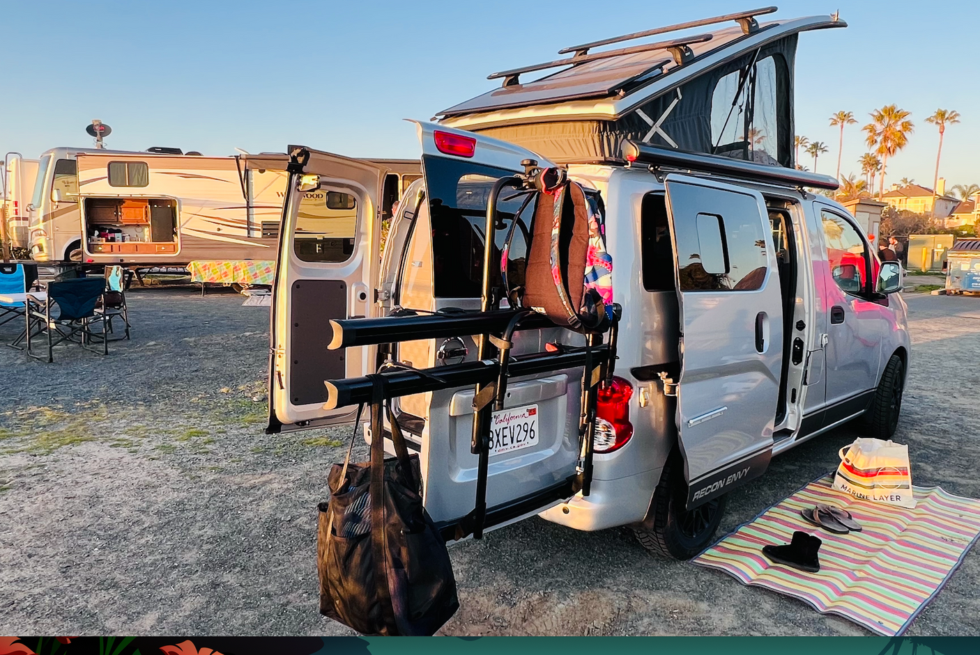 RV rental adventure: A silver camper van with a pop-top tent and a large RV with an outdoor kitchen, set up for camping.