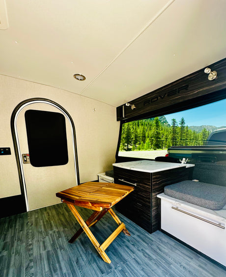 Step into your next RV rental adventure! Cozy interior with compact kitchen, foldable table, comfy bench, and mountain views.