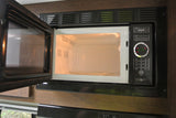An open microwave oven with an illuminated interior and a digital display showing "08:17" in an RV rental kitchen.