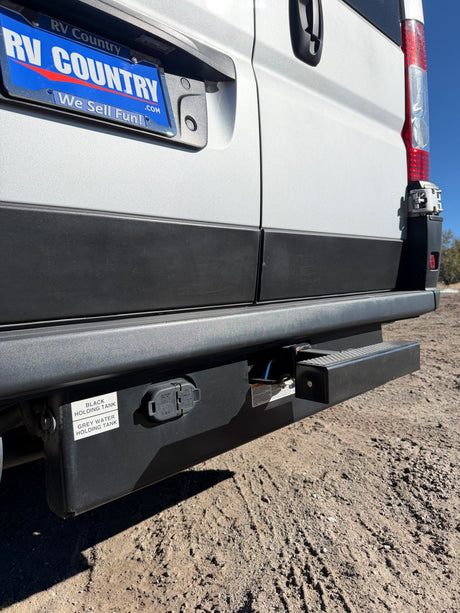 Rear of an **rv rental** camper van, revealing essential black and grey holding tanks, trailer hitch, and electrical connector for travel.