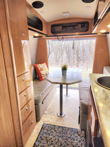 Cozy RV rental interior: dining area, kitchen, and window view for your next adventure.