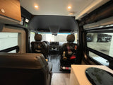 RV rental interior: looking forward past rear seating towards cockpit, with kitchenette counter on right.