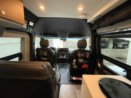 RV rental interior: looking forward past rear seating towards cockpit, with kitchenette counter on right.