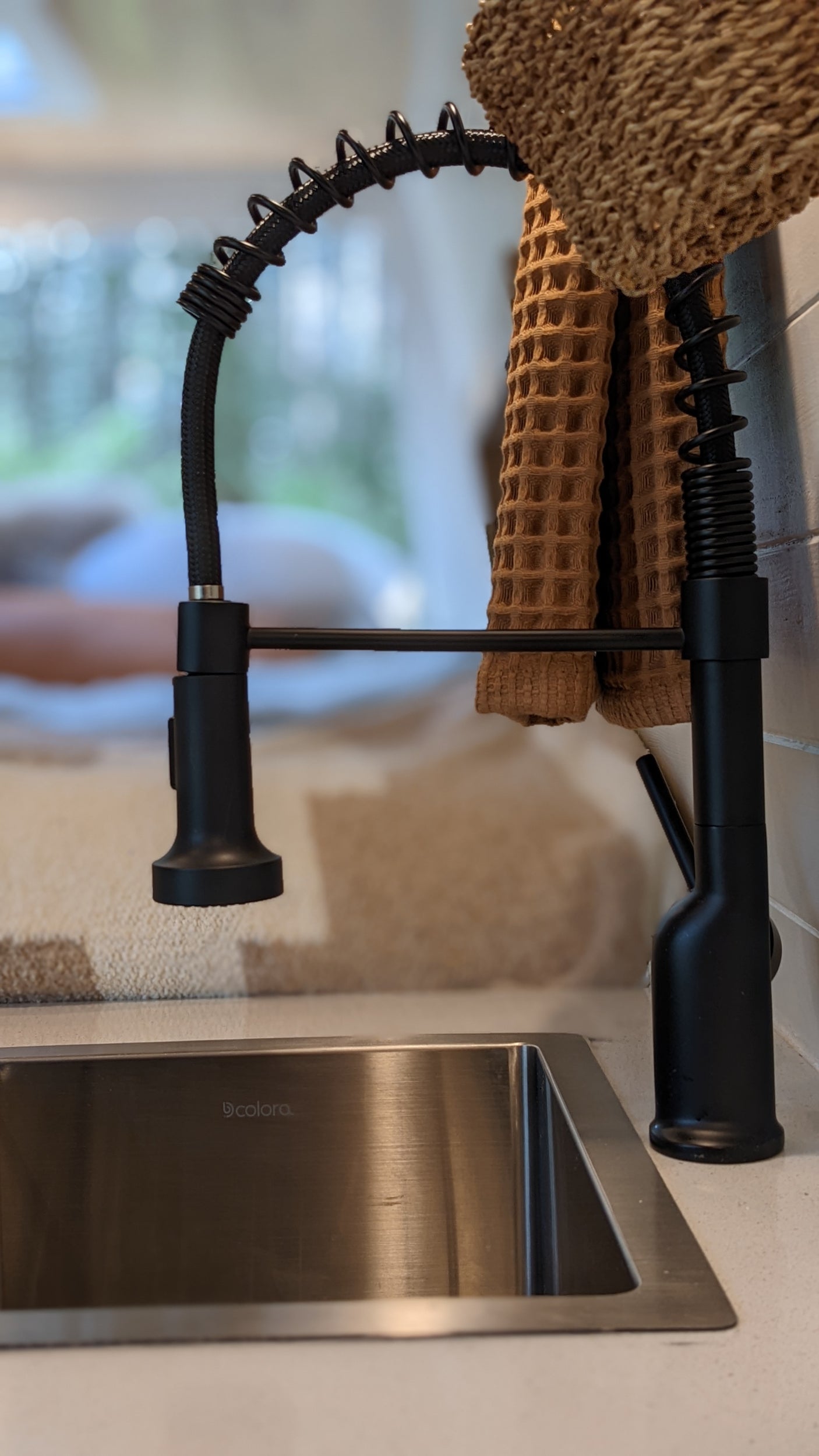 Modern black kitchen faucet and stainless steel sink with a brown towel, ideal for an RV rental.