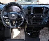 Inside a modern RV rental: the driver's cockpit. Features a steering wheel, dashboard with central screen, and dash-mounted gear shift.