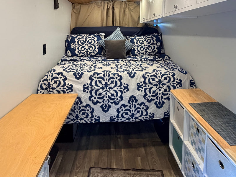  with an RV rental parked nearby in a scenic outdoor setting.|Enjoy an RV rental adventure! A white camper van with an open side door is parked at sunset among rocks and trees — photo 4