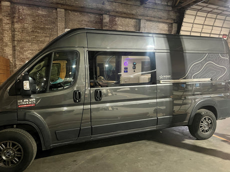 Gray NOKE Van Co. Ram ProMaster camper van with topo graphics, equipped for RV rental journeys. See inside controls.