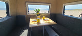 Enjoy your RV rental with a stunning beach view from this cozy dining area, complete with flowers and drinks.