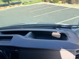 RV rental dash & windshield view, facing a sunny parking lot. Dashboard compartment, vents, and windshield sticker visible.