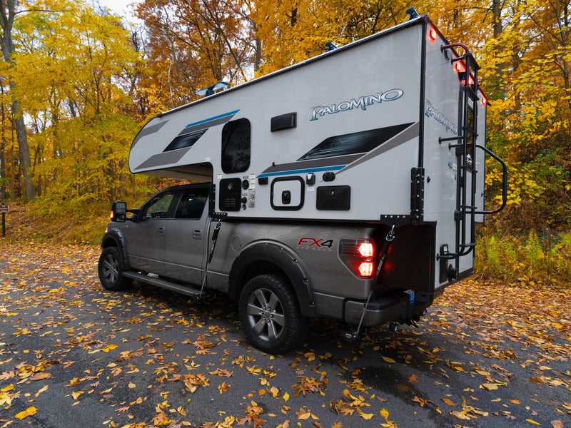  ready for adventure.|Experience fall adventure! This grey Ford F-150 truck with a Palomino RV rental camper unit is set amidst vibrant autumn foliage.|Autumn RV rental adventure: F-150 truck with a Palomino camper parked on a leaf-strewn road — photo 3