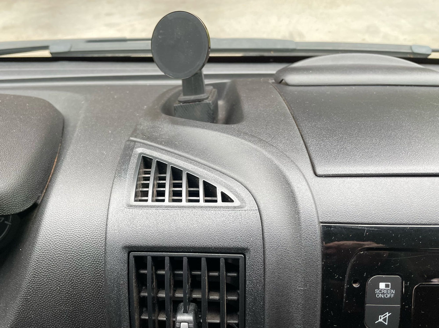 Dashboard view inside an RV rental, showing a magnetic phone mount, air vents, and screen controls. Typical vehicle interior.