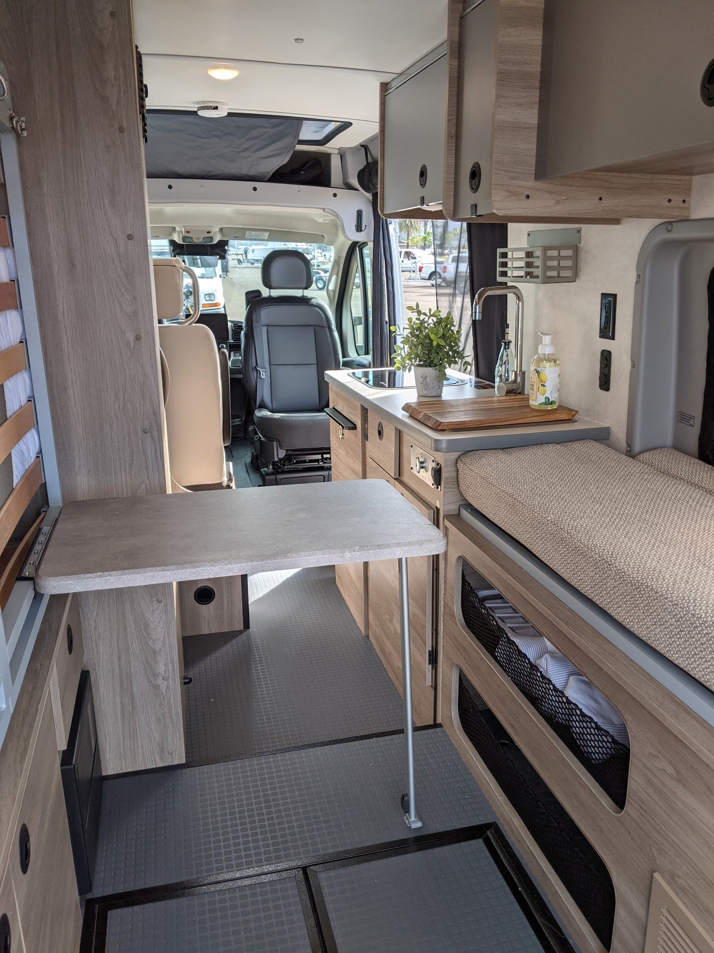  and windows overlooking a bay with boats.|Spacious RV rental interior with a cozy bed & scenic ocean view. Perfect for van life adventures!|Inside a modern rv rental — photo 4