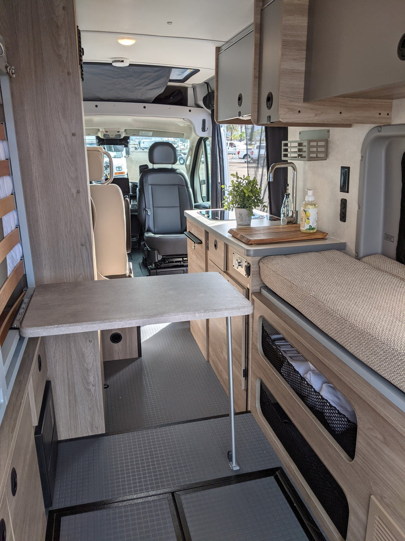 and windows overlooking a bay with boats.|Spacious RV rental interior with a cozy bed & scenic ocean view. Perfect for van life adventures!|Inside a modern rv rental — photo 4