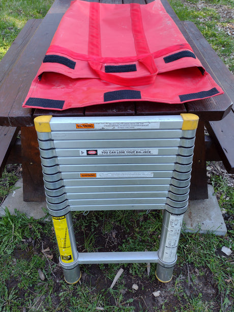 Compact telescoping ladder & carry bag, a practical accessory for RV rental trips. Visible safety warnings highlight safe use.