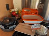 Compact camping kitchen setup in an RV rental, featuring nested pots, a cutting board, and cooking tools for outdoor experiences.