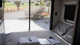Cozy RV rental bedroom with a comfortable bed, fresh towels, and a tranquil view of the fenced outdoors.