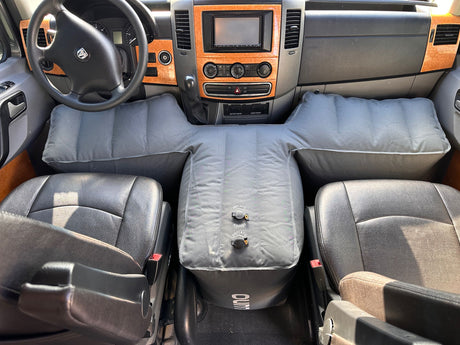 RV rental front cabin showcasing an inflatable mattress system that fills the space between the driver and passenger seats, creating a bed.