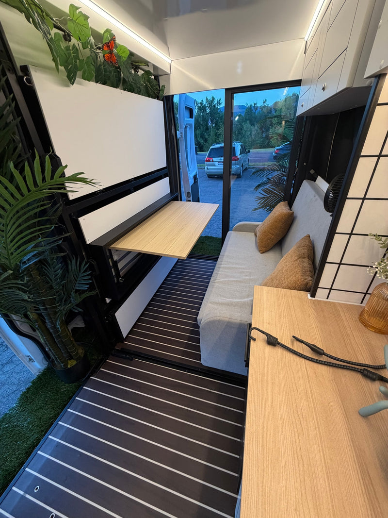 Cozy RV rental interior with a convertible sofa, fold-down table, and lush decor. Ideal for modern van life adventures. — photo 11