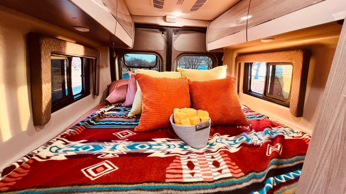  hills & bare trees in the background.|A silver RV rental van from Beckon Rentals with a happy couple inside & their dog by the open side door — photo 9