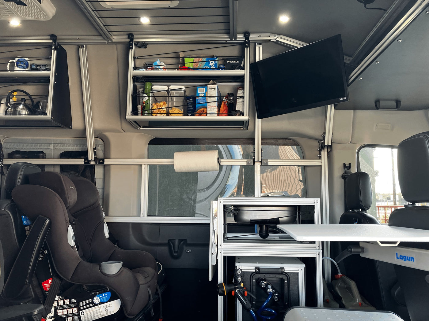 RV rental interior: Organized camper van kitchen, storage, TV, and child seats. Perfect for family trips! — photo 14