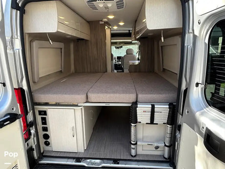 Inside our RV rental: a modern camper van with a flexible bed setup, under-bed storage, and utility controls.