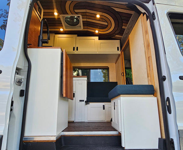 Custom camper van interior for RV rental, featuring a stylish kitchen, patterned ceiling, and cozy seating.