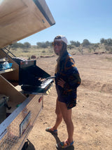 Happy camper: Woman smiles while cooking on a portable stove from her rv rental teardrop trailer.