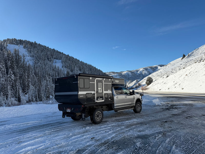 Rugged Four Wheel Campers Hawk+ truck camper on icy winter roads, surrounded by snowy mountains. Perfect for an rv rental adventure. — photo 4
