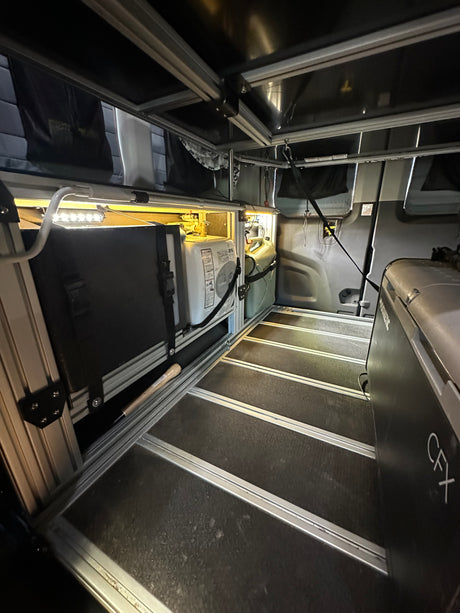 RV rental interior shows a Dometic fridge, water heater, and water jug in a modular camper van setup with LED lighting.