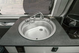 RV rental kitchenette: Sink, faucet, induction cooktop with a pot, and a scenic window view.