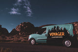 A Voyager campervan RV rental is parked by desert mountains under a starry night sky, ready for adventure.