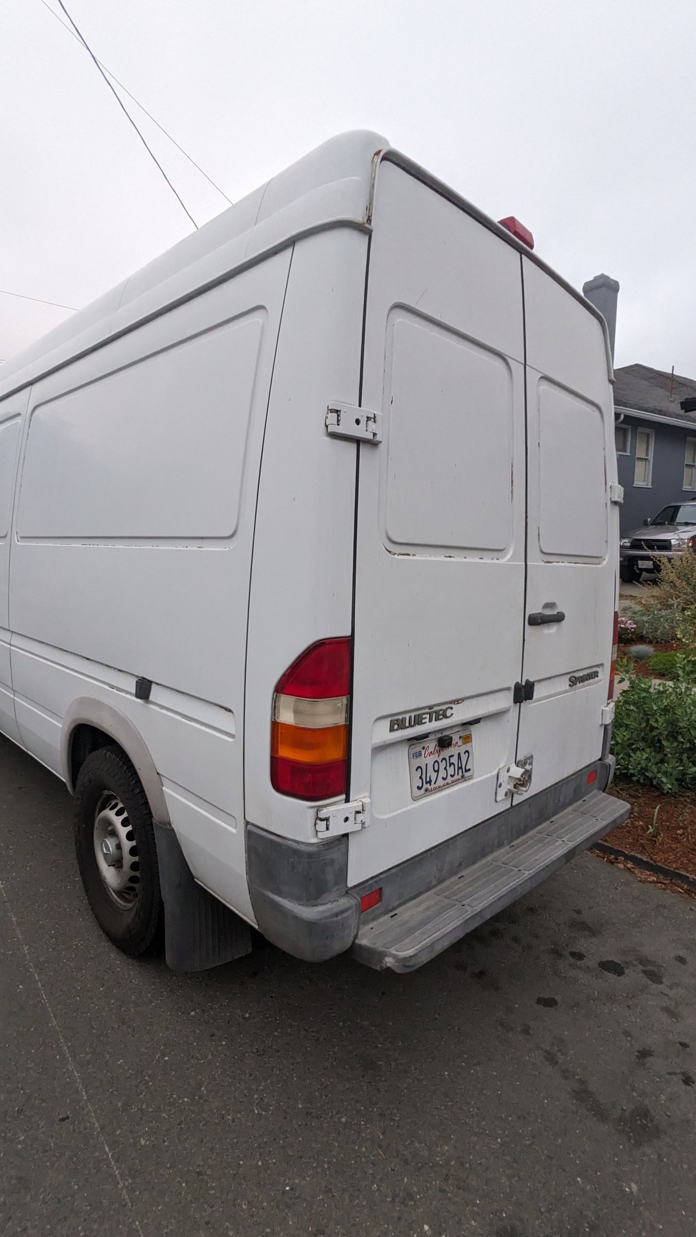 White Mercedes Sprinter van, excellent for RV rental. Rear view, California plate 34935A2, parked on asphalt.