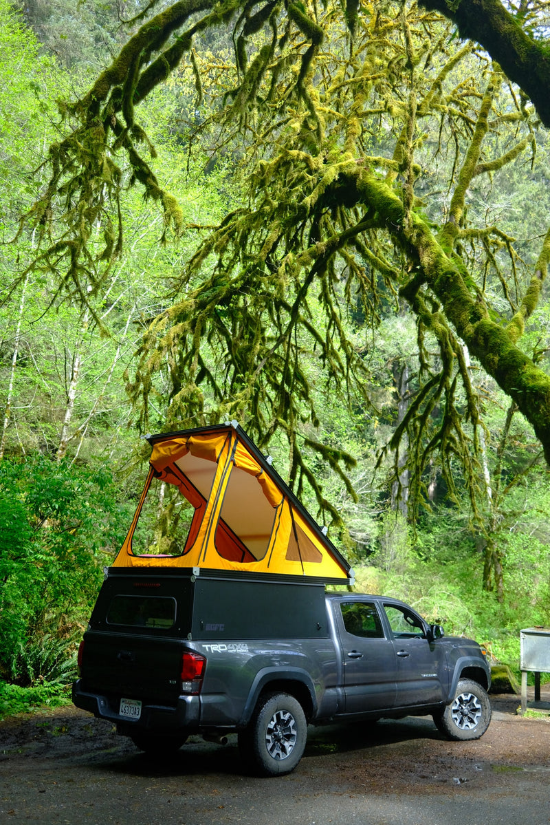  offering a compact rv rental option for exploring rugged terrain.||RV rental: A grey pickup truck with an orange pop-up camper parked under mossy trees in a lush forest. Ready for adventure.|| — photo 7