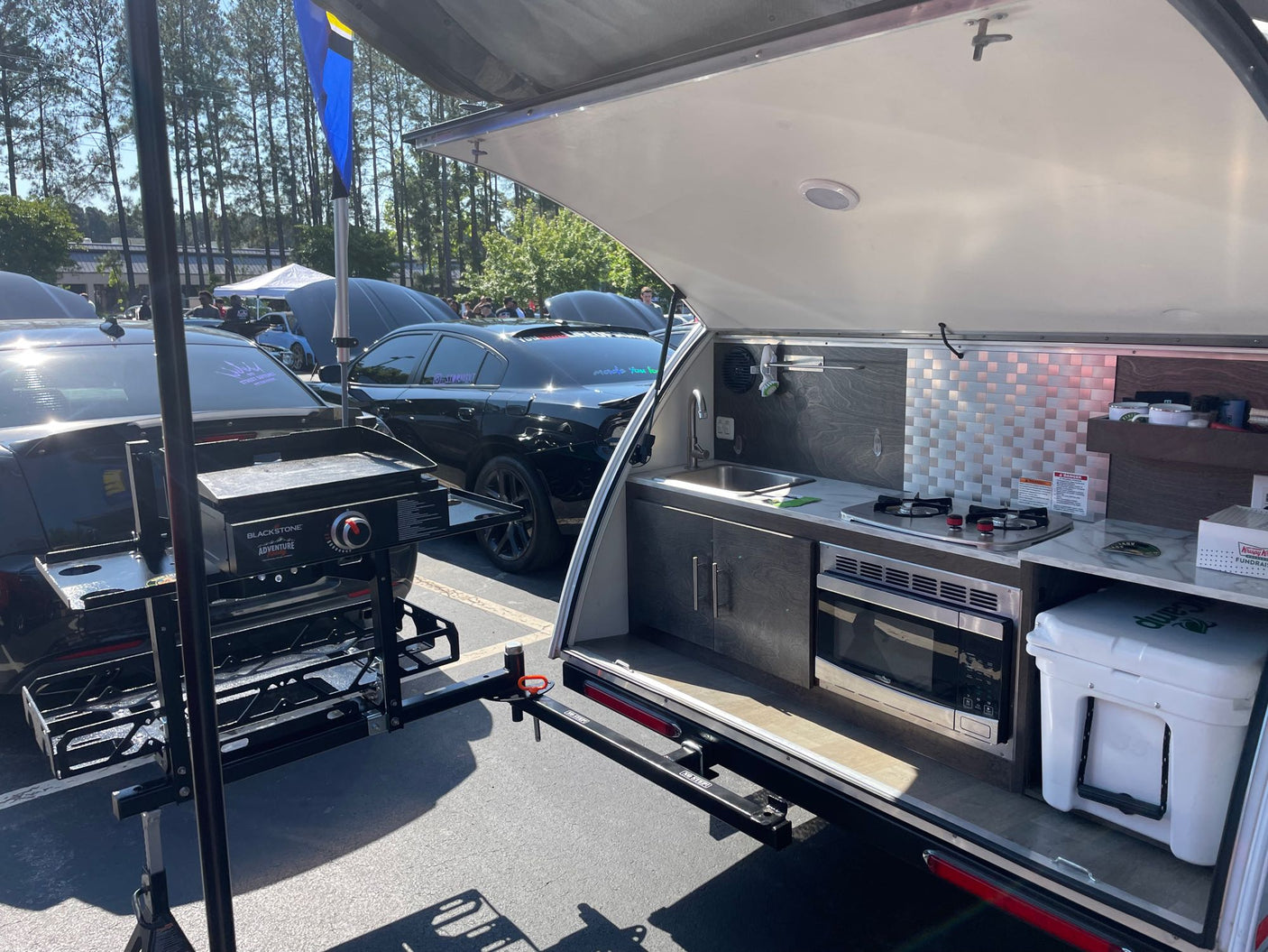 Discover this RV rental's impressive outdoor kitchen in a compact trailer, featuring a sink, stove, microwave, and a separate griddle.
