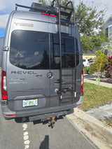 Rear view of a gray Winnebago Revel 4x4 Sprinter RV rental with ladder, tow hitch & Florida plate.