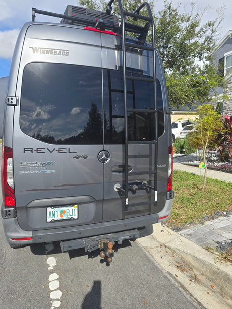 Rear view of a gray Winnebago Revel 4x4 Sprinter RV rental with ladder, tow hitch & Florida plate.