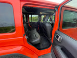 Open rear door of a vibrant orange Jeep with black leather seats. Spacious interior, ready for your RV rental adventure!