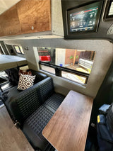 Explore this modern RV rental's interior: comfy dinette with quilted seats, wood table, & digital panel for lights and systems.
