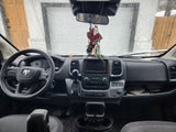 Inside a modern rv rental van: rainy windshield view, Ram dashboard with steering wheel, infotainment, and gear shift.