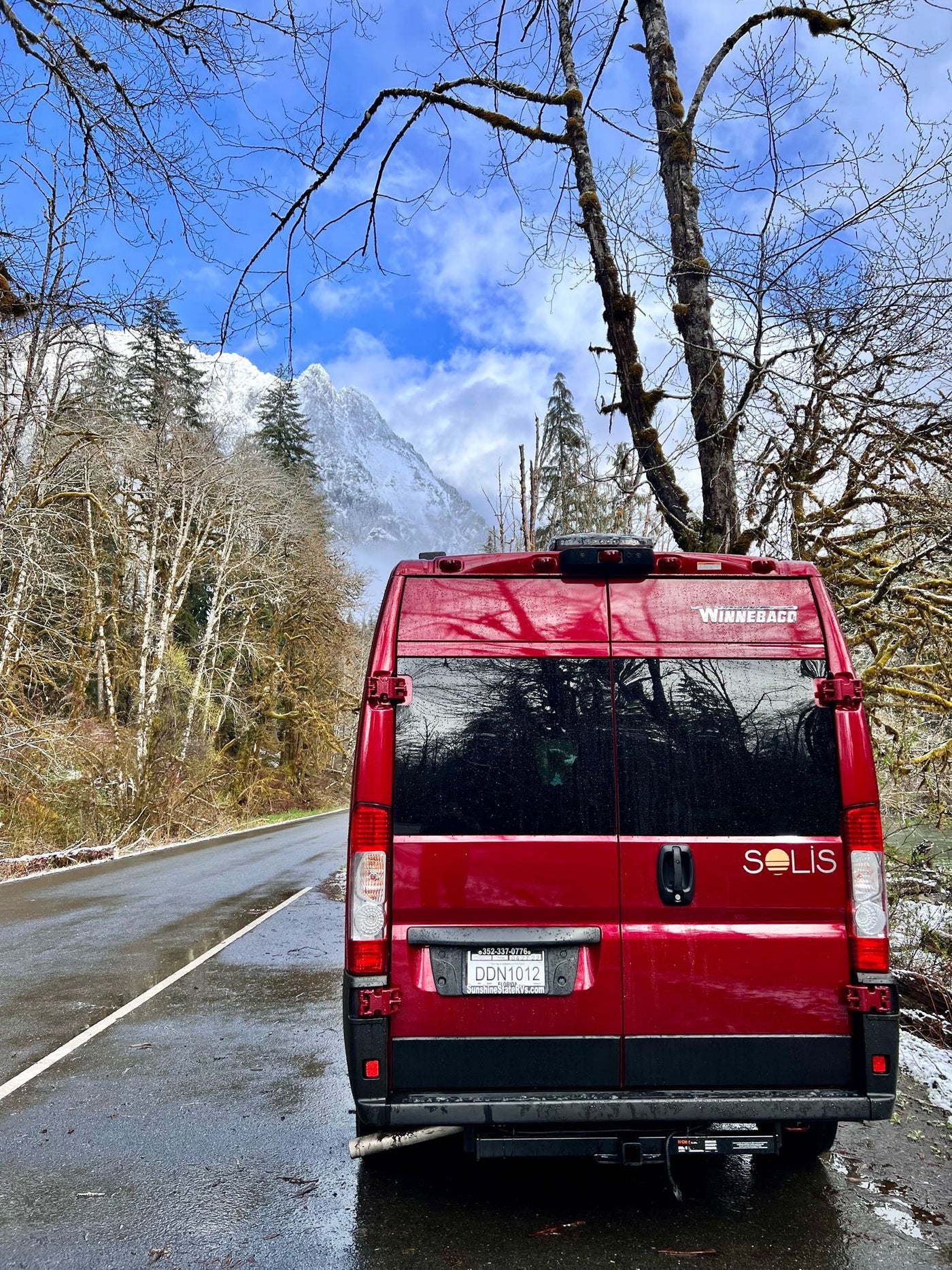  parked on a gravel road in a forest. Perfect for outdoor camping and road trips.|This red Winnebago camper van with an open sliding door showcases its RV interior and pop-top roof — photo 5