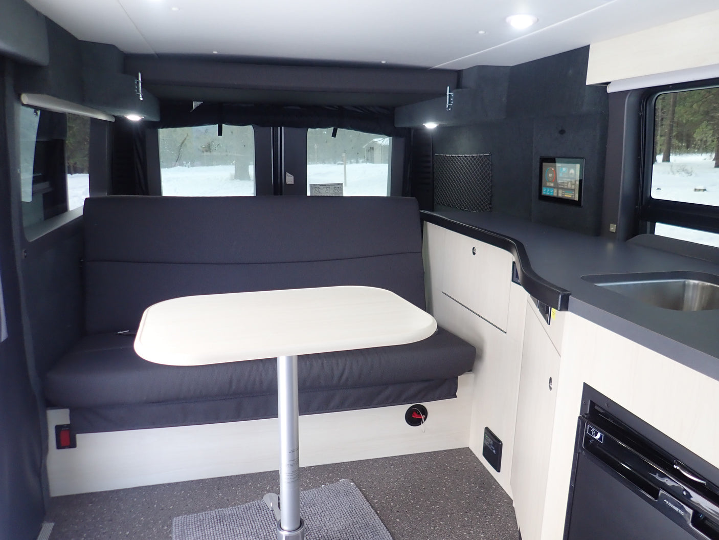 This **RV rental** offers a spacious interior: dining with bench seating, a table, and a functional kitchen setup.