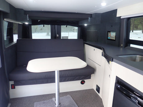 This **RV rental** offers a spacious interior: dining with bench seating, a table, and a functional kitchen setup.