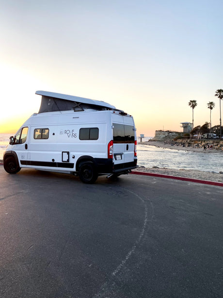 A white Rove Vans camper van rental, with its pop-top extended, parked beachfront at sunset for a perfect RV adventure.