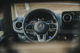 Inside a Mercedes-Benz RV rental: a detailed view of the steering wheel, controls, and modern dashboard.