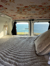 Cozy rv rental bed with scenic ocean view and a seagull outside. Perfect for coastal adventures!